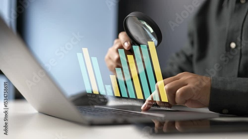 Analyzing digital bar graphs on a laptop with magnifying glass