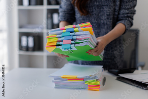 Fotografie Close up of hands working in Stacks of paper files for searching and checking unfinished document achieves on folders papers on desk