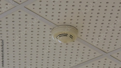 The fire alarm sensor on the ceiling of the concert hall is attached to perforated acoustic panels.