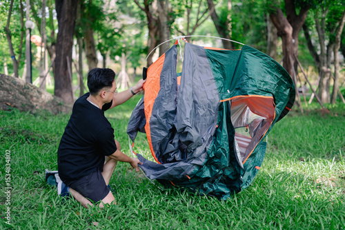 Wallpaper Mural Man sets up a colorful tent in a lush green park on a sunny day surrounded by trees and nature Torontodigital.ca