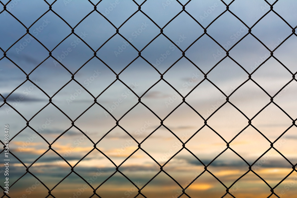 Fototapeta premium Old metal wire fence rust on the evening sky background.