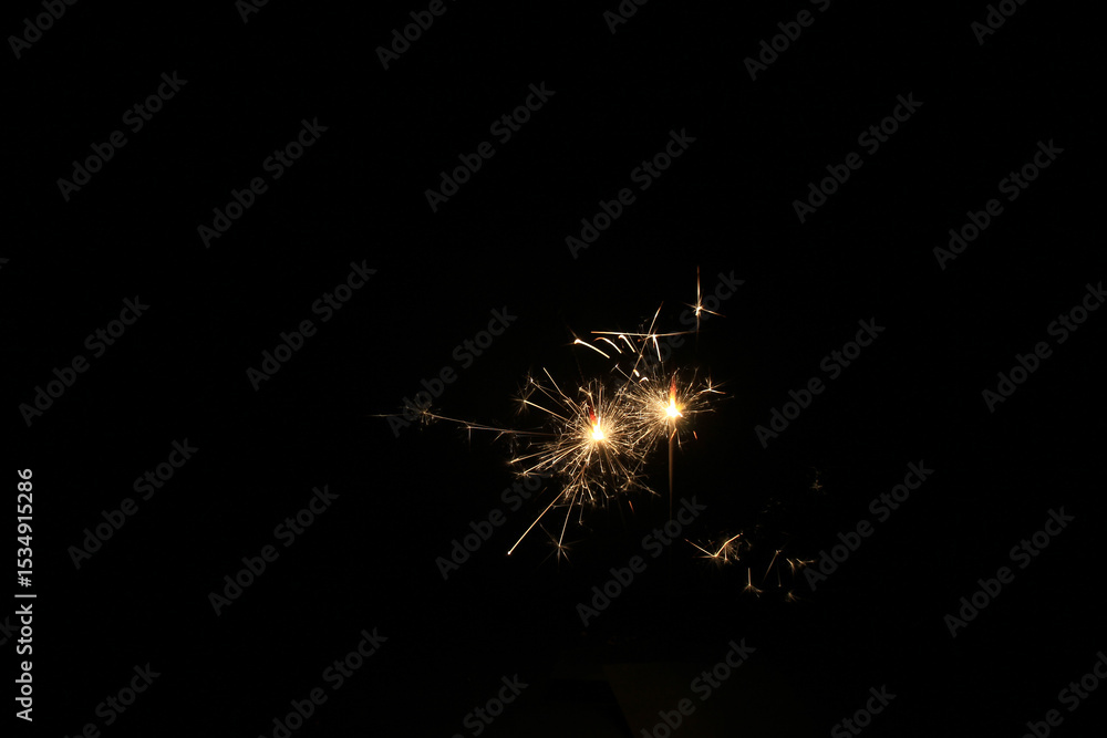 Fototapeta premium Yellow sparks fly on a black background, layered with grain, noise, and glowing effects to give a gritty, cinematic feel full of motion, contrast, and intense visual energy.