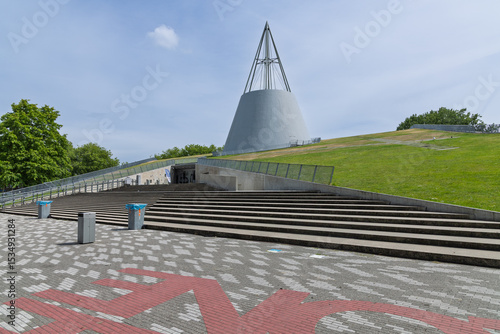 The iconic TU Delft Library building, featuring a distinctive conical roof and a sloping green roof, a landmark of modern architecture.