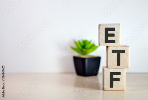 ETF - text on wooden cubes, on wooden background. Flower in a pot