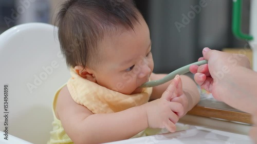 8 month old baby learning to eat for the first time. The concept of a child who has difficulty eating, playing while eating.