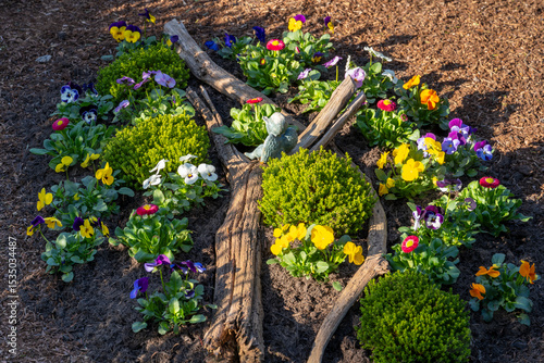 Kleines Blumenbeet mit Stefmütterchen (Viola) und Dekoration, Pinienrinde außen herum