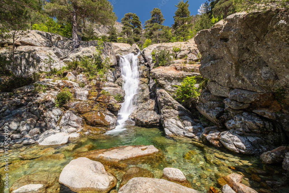 Obraz premium Water cascades over the Cascade des Anglais on the L'Agnone river through the forest and mountains of the GR20 trail at Vizzavona on the Mediterranean island of Corsica