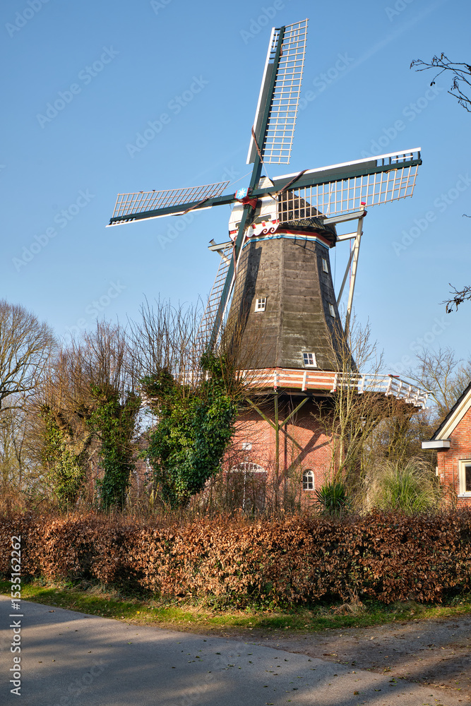 Obraz premium Hulling mill De Vier Winden in Pieterburen with Four Sails under Bright Blue Sky