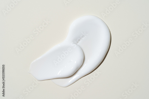 White cosmetic cream texture, skincare lotion swatch on light beige background. Face creme, body moisturizer, hair conditioner smear smudge stroke. Creamy beauty product closeup