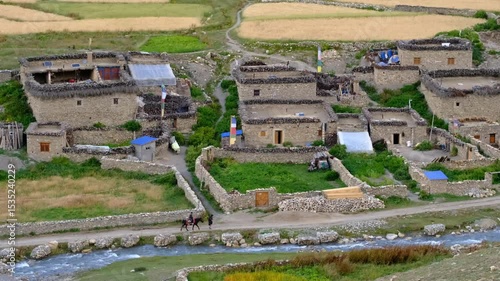 This stunning aerial drone shot captures a small traditional mountain village nestled in a rugged landscape.