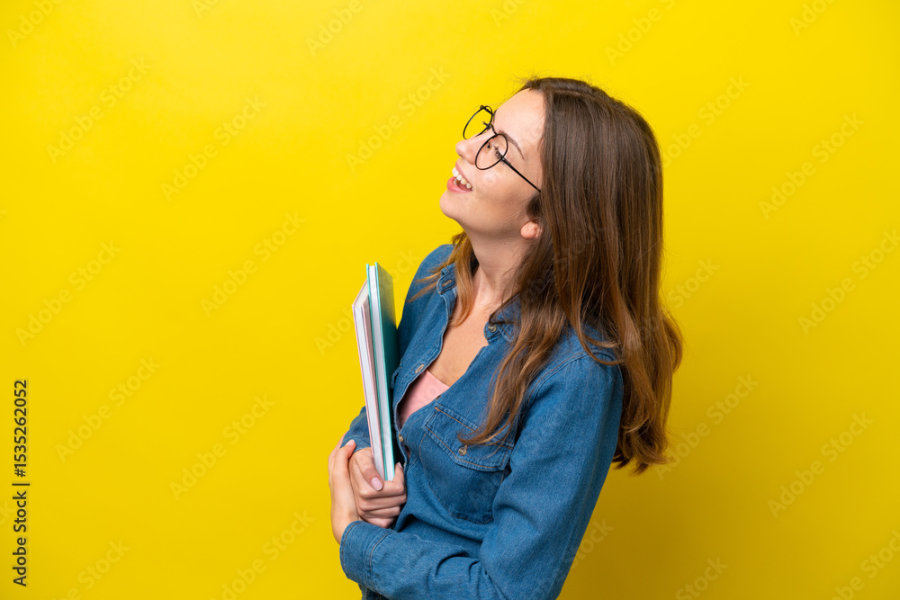 Young student caucasian woman isolated on yellow background laughing in lateral position Young student caucasian woman isolated on yellow background laughing in lateral position