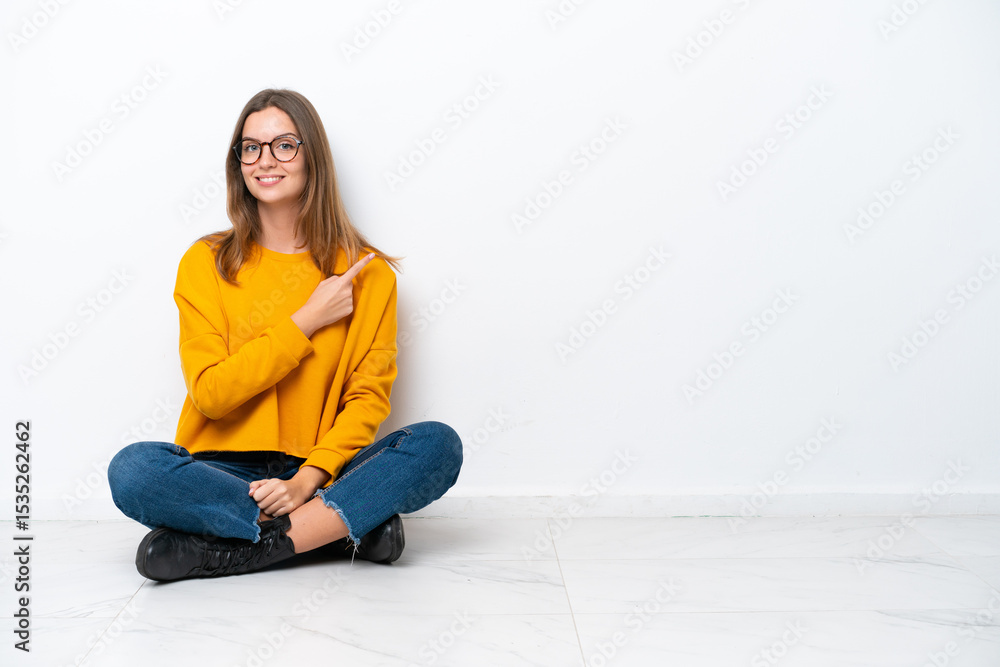 Young caucasian woman sitting on the floor isolated on white background pointing to the side to present a product Young caucasian woman sitting on the floor isolated on white background pointing to the side to present a product