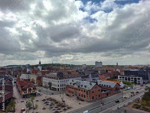 denmark aalborg june 11 2024 Aerial view of a vibrant city square featuring historic buildings, busy streets, and a cloudy skyline.
