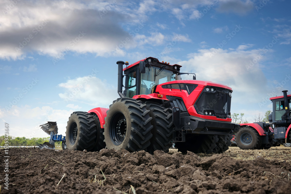 Close-up of a plowed field. In the background are large modern tractors red color with a plow. Close-up of a plowed field. In the background are large modern tractors red color with a plow.