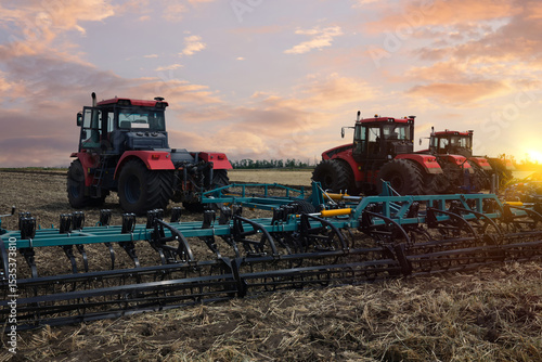 Картината върху платно Several large tractors stand in a field against the backdrop of a sunset sky