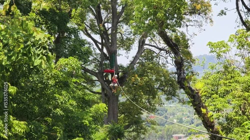Woman is enjoying an exhilarating ride on a zip line that traverses the thick woods surrounding her