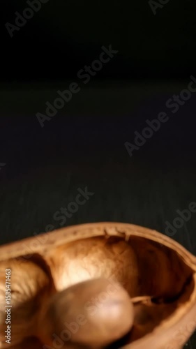 Wallpaper Mural Close-up of a dried pecan nut inside its cracked brown shell on a dark surface with dim lighting, showcasing texture and natural elements Torontodigital.ca