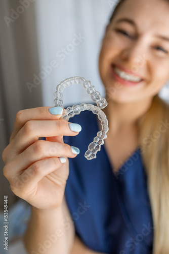 Smiling woman holding clear aligners for teeth straightening and dental care
