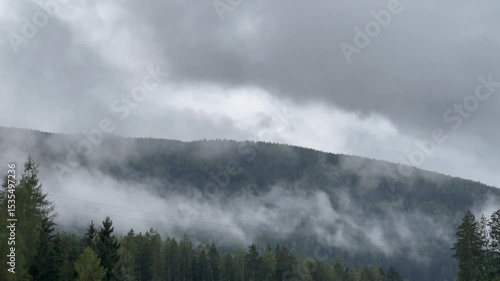 Low fog slowly drifting over mountain ridge on a cloudy day.