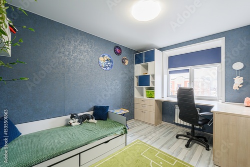 Fotografie modern child's room with blue textured walls, a bed with green cover, a desk by