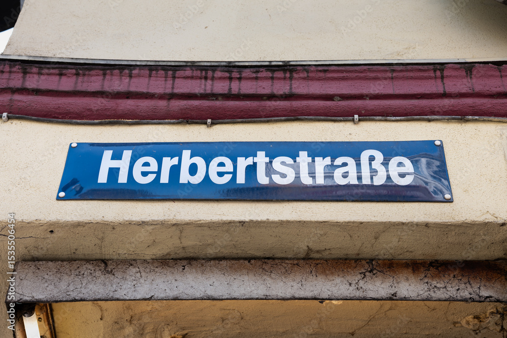 Fototapeta premium Herbertstrasse street name sign close-up in Hamburg, Germany. Road signage at the intersection in the red-light district of St. Pauli. Famous place known for prostitutes in the windows of the houses.