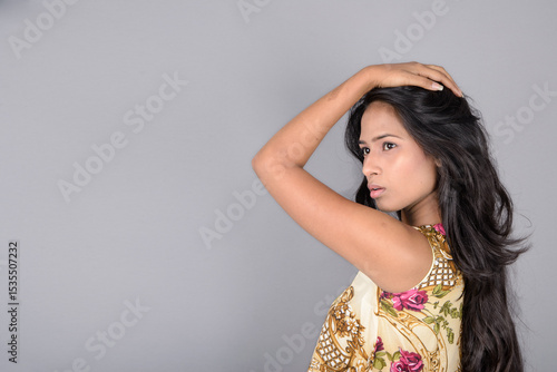 A charming young woman wearing a floral patterned top, black leggings and black heels, posing with jovial facial expressions and different emotions showcasing modern style, elegance.