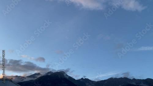 Mountain peaks with low clouds under clear blue sky