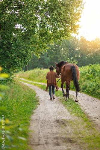 Woman walking with a horse on a path