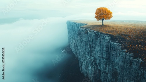 Solitary autumn tree atop a craggy cliff, mist-shrouded landscape