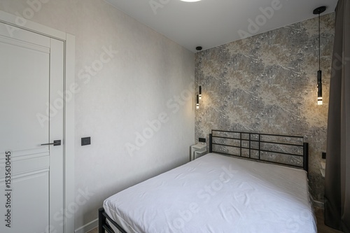 modern bedroom with a white bed, black metal headboard, and patterned wallpaper. Pendant lights hang above matching bedside tables. Curtains frame a window with a city view