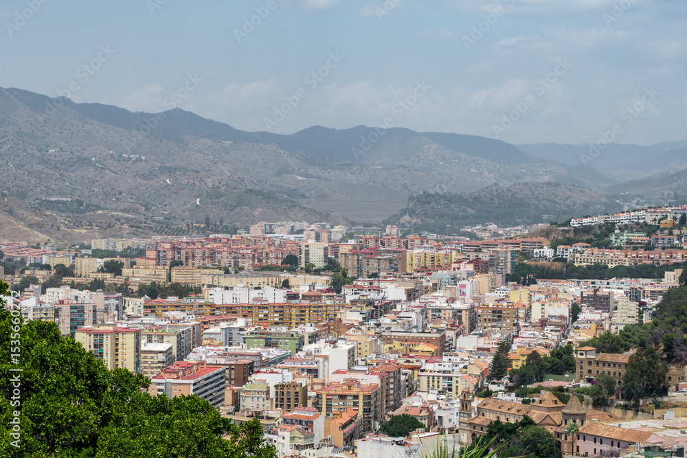Naklejka premium Title: Modern Málaga cityscape with iconic twin towers and residential neighborhoods seen from the elevated Gibralfaro viewpoint.