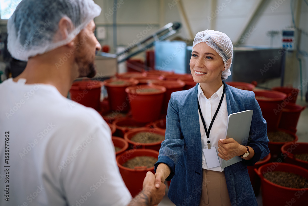 Obraz premium Happy company owner handshaking with her worker in food processing plant.
