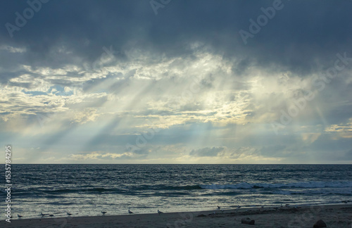 Pacific Ocean with sun rays through dark stormy clouds 