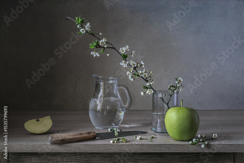 Still life with an apple and a blooming cherry twig.