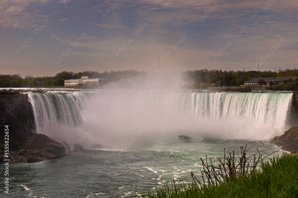 Fototapeta premium A dramatic view of Niagara Falls’ Horseshoe Falls, with turquoise water plunging into a misty abyss.