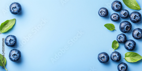 Fresh blueberries with green leaves flat lay on light blue background. Healthy berry and nutrition concept. Image for banner with copy space.
