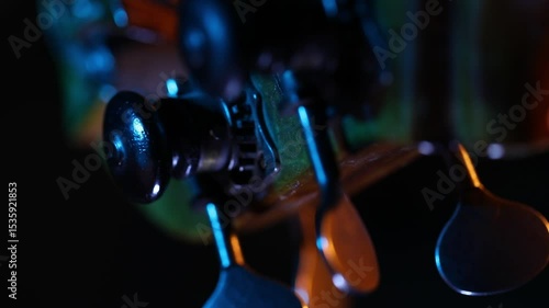 A dramatic close-up rack focus reveals the wooden bridge and strings of a cello. Moody blue and orange light creates a cinematic atmosphere against a dark background.