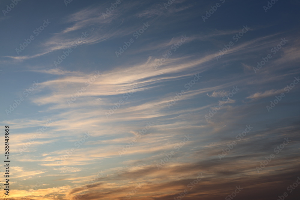 Obraz premium Stunning sky filled with light, fluffy clouds resembling brush strokes, blending soft colors of blue and orange, creating a peaceful and calming ambiance in nature