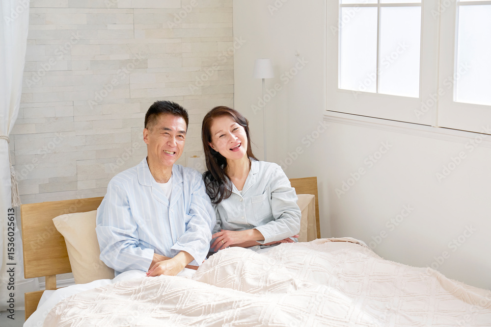 Fototapeta premium ベッドの上の中年の夫婦 笑顔 ポートレート