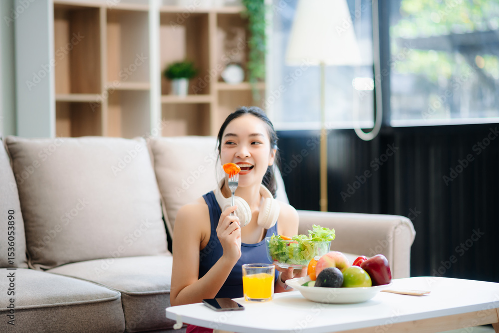 wellness as a cheerful woman enjoys a salad and fruits while engaging with technology at home wellness as a cheerful woman enjoys a salad and fruits while engaging with technology at home