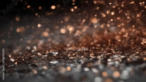 A close up shot showing scattered golden particles on a dark surface with bokeh light in the background