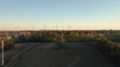 Wind turbines generate renewable energy at sunset in a vast rural landscape with vibrant colors
