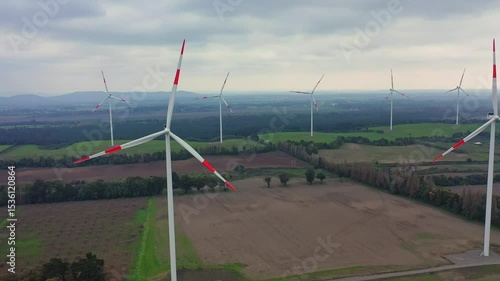 Wind turbine stands tall over lush green fields in rural area during daytime