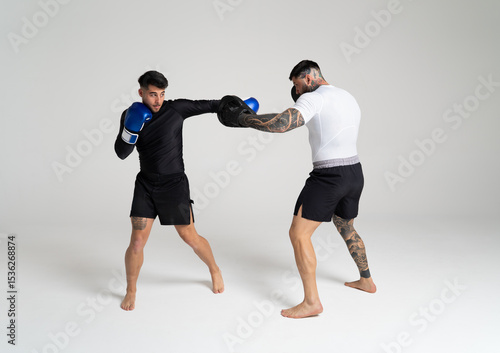 Two male mma fighters training together, throwing punches in boxing gloves