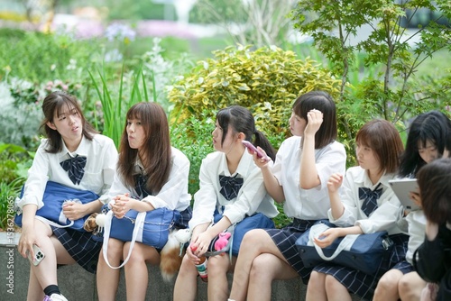 Canvas Print In early summer in Shanghai, near The Bund, Japanese high school girls in uniforms sit at a street corner, chatting and laughing, their smiles adding a touch of youth to the vibrant city atmosphere