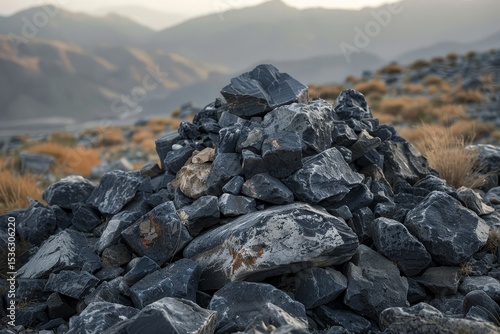 Dark rocks piled high on a hillside with hazy mountains in the background