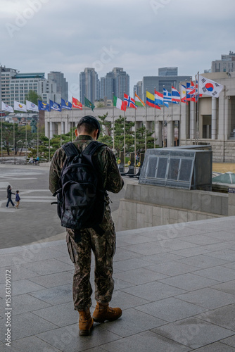 South Korean soldier standing in front of the flags of the united nations