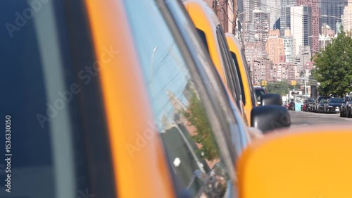New York City. Row of yellow Taxi cars on street, Queens. Many taxi cabs on avenue, Long Island, LIC. Medallion taxicab and Manhattan Midtown urban skyline cityscape. High-rise building architecture.