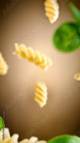 Delicious spiral pasta with fresh basil leaves flying on silver fork ready to eat gourmet Italian dish, culinary concept