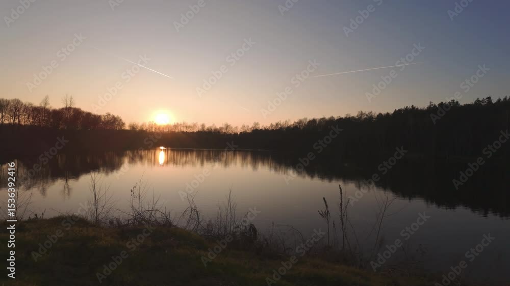 A breathtakingly stunning sunset beautifully reflects on a serene, calm lake, which is surrounded by gorgeous trees A breathtakingly stunning sunset beautifully reflects on a serene, calm lake, which is surrounded by gorgeous trees